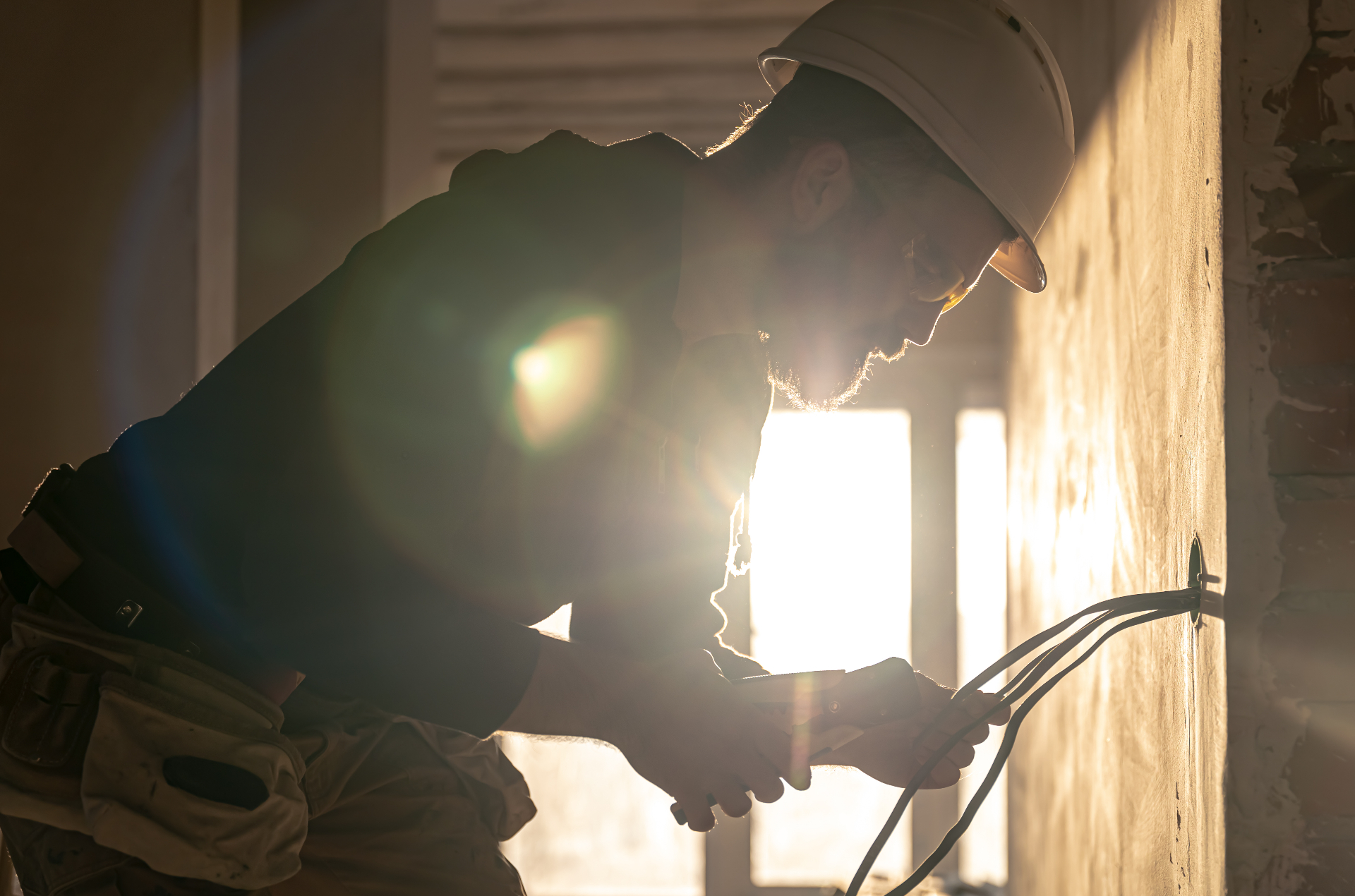 Elektriker bei Verkabelungsarbeiten im Gegenlicht
